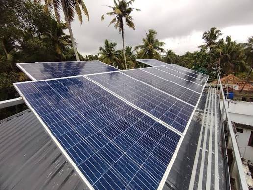 Solar panels installed on a metal roof with palm trees nearby